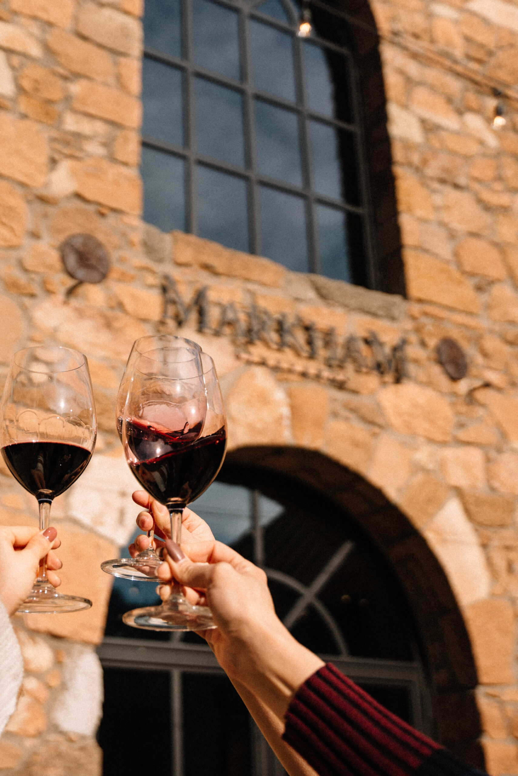 REd Wine Glasses toasting in front of the Markham Stone Cellar