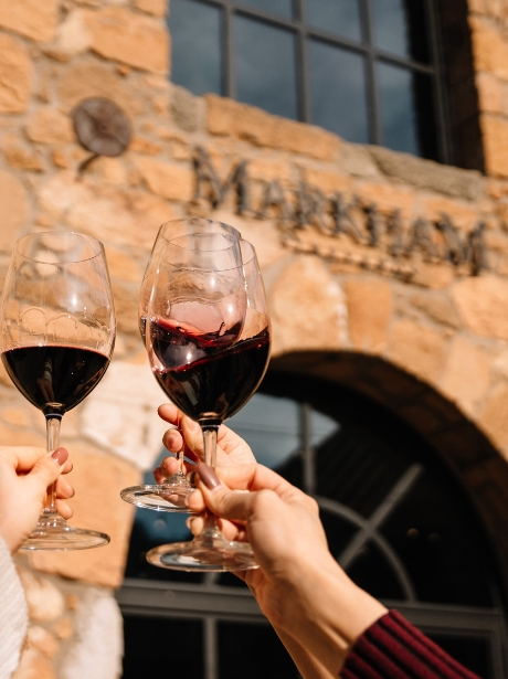 Wine Glasses cheersing in front of Historic Stone Cellar